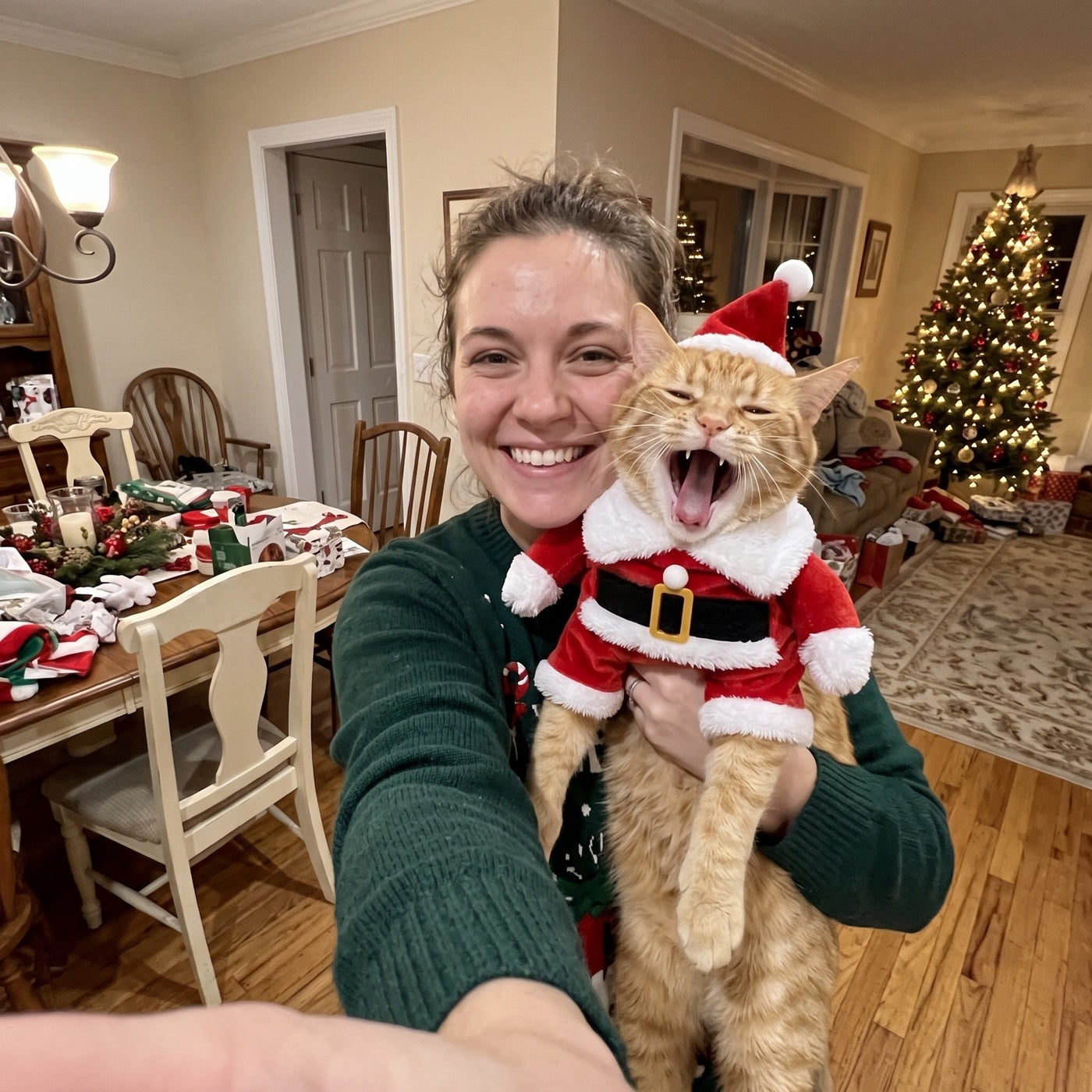 Mia holding her orange cat in the FestiveWhiskers Santa suit